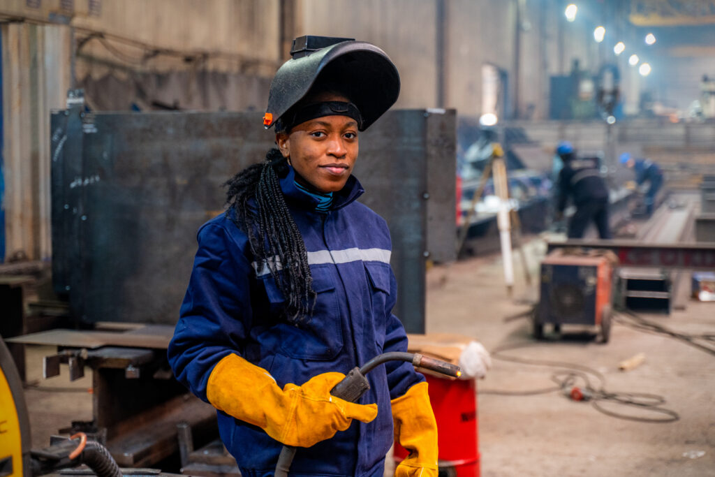 A young person holding welding equipment on a work site. 